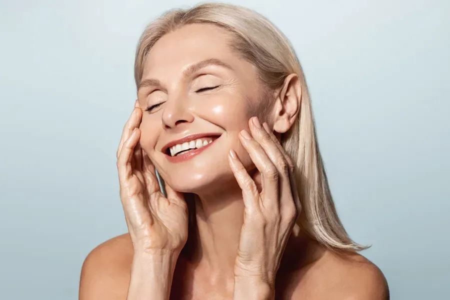PRP-Facelift-Facial-Doctor A beautiful mature blonde woman touches her face, happy with her PRP facelift and facial injections from Genifer Chavez, MD in Tucson.